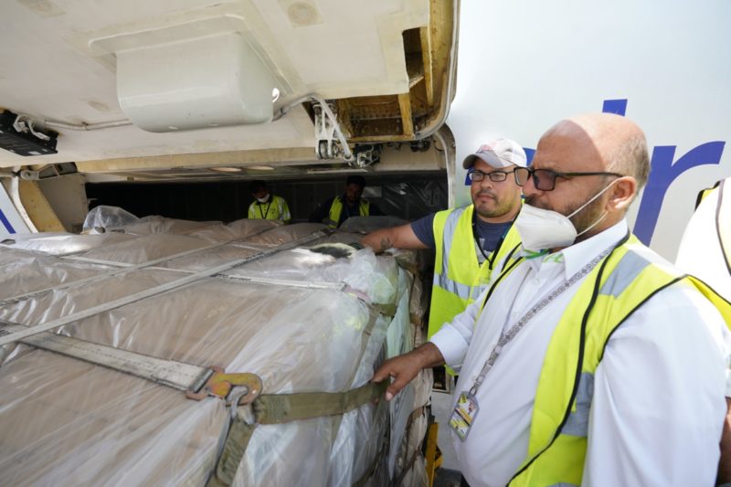 a group of men wearing safety vests and standing next to a large cargo plane