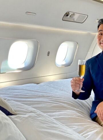 a man sitting on a bed holding a glass of champagne