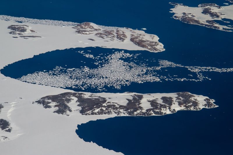 an aerial view of an island with ice and water