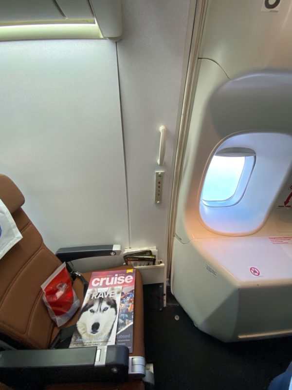a seat on an airplane with a magazine and a window