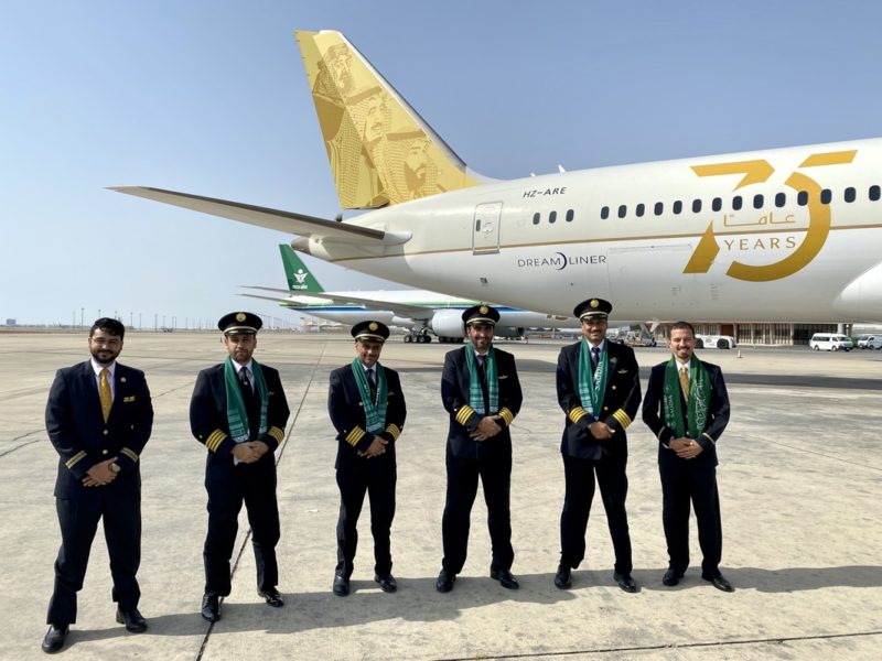 a group of men in uniform standing in front of an airplane