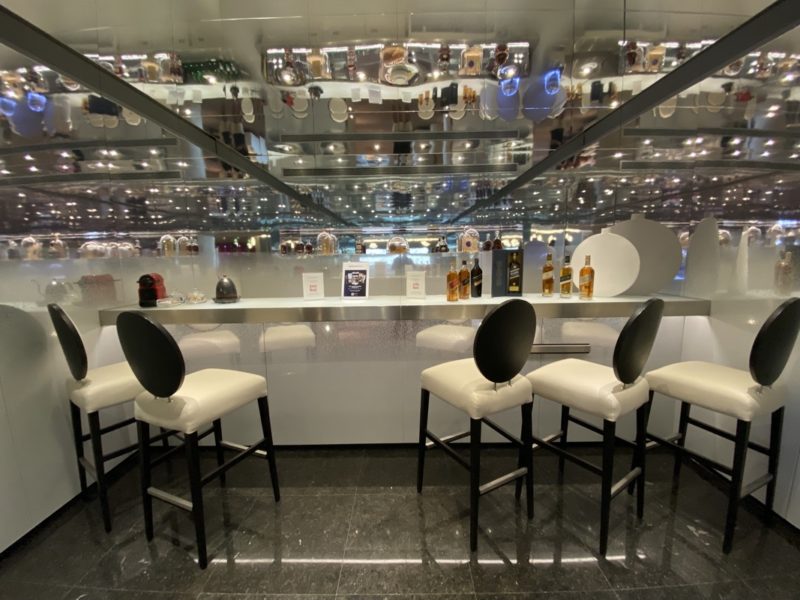 a bar with white chairs and a glass ceiling