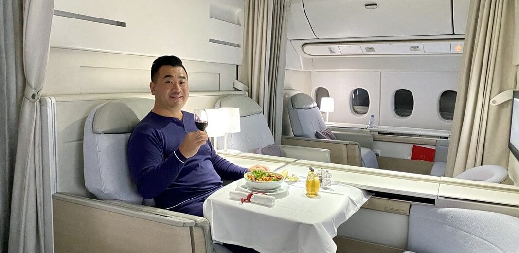 a man sitting in a chair with a plate of food and a glass of wine