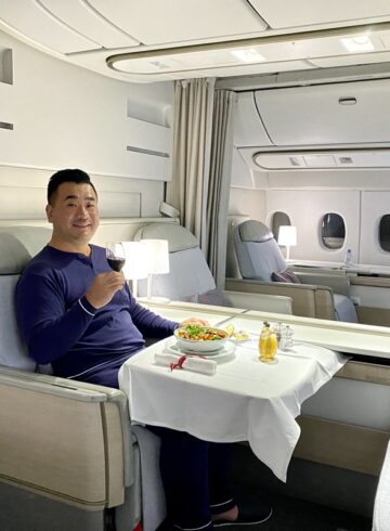 a man sitting in a chair with a plate of food and a glass of wine