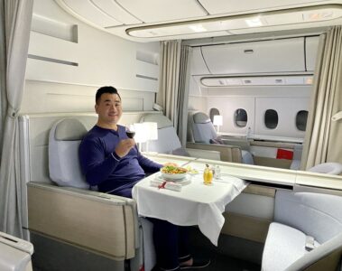 a man sitting in a chair with a plate of food and a glass of wine