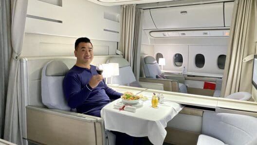 a man sitting in a chair with a plate of food and a glass of wine
