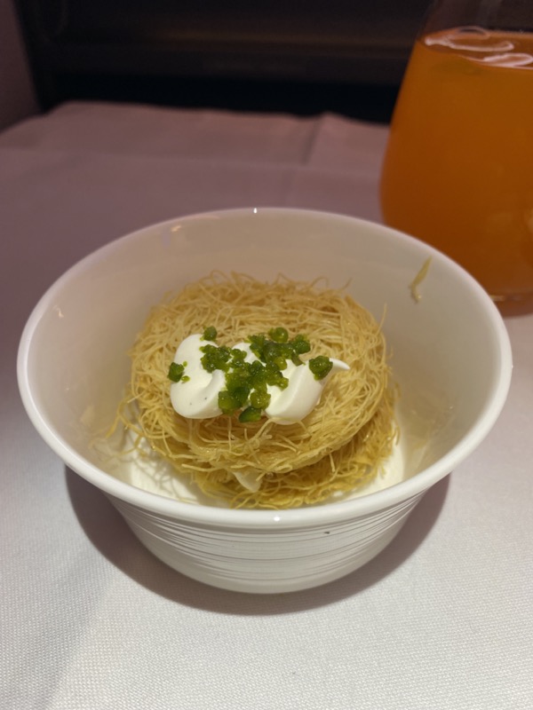 a bowl of noodles with cream and green toppings