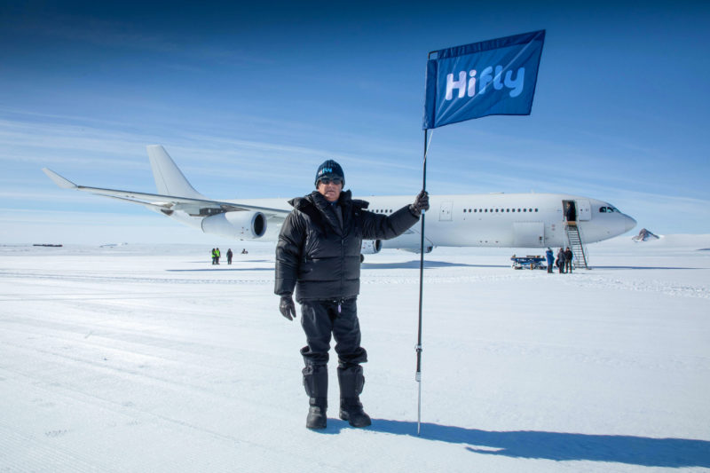 a man holding a flag in front of an airplane