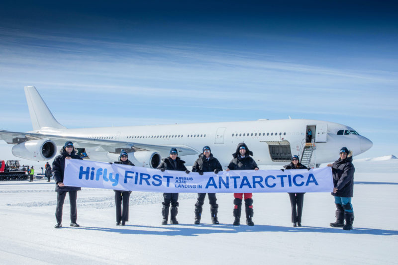 a group of people holding a banner in front of an airplane