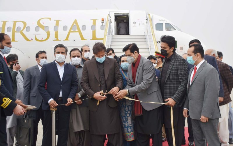 a group of people wearing face masks cutting a ribbon