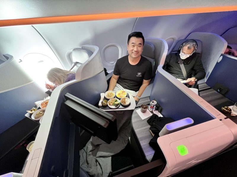 a man sitting in a plane with food on the table