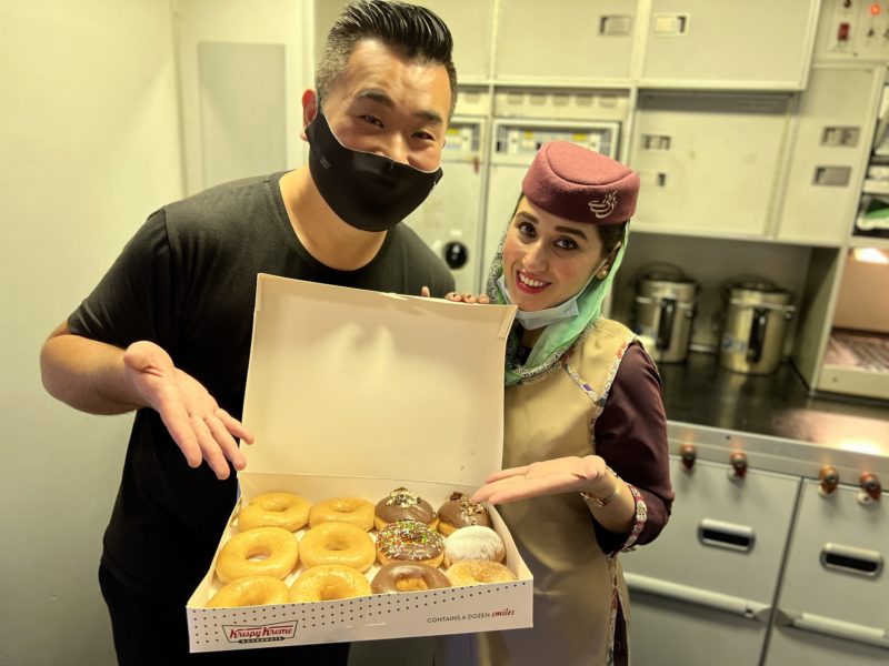 a man and woman holding a box of doughnuts