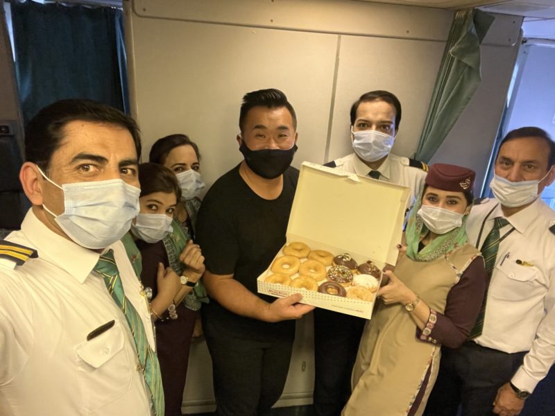 a group of people wearing face masks holding a box of donuts