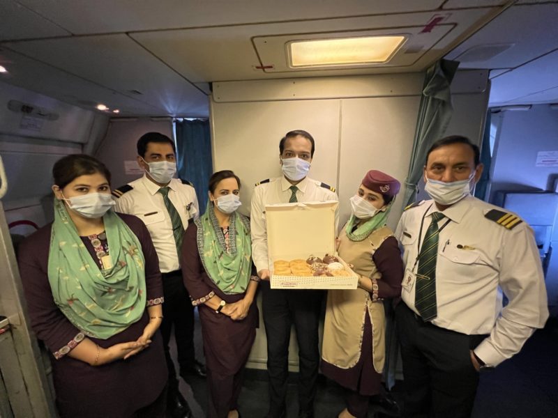a group of people wearing face masks and holding a box of food