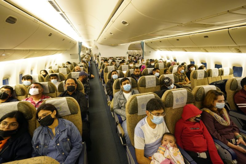 a group of people in a plane with face masks