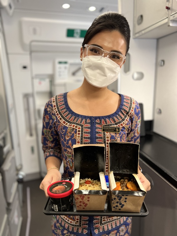 a woman wearing a mask holding food in a container