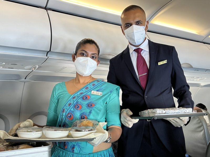 a man and woman wearing face masks holding food on a tray