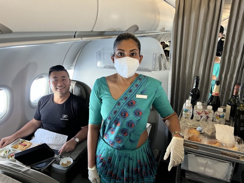 a woman wearing a face mask and gloves standing in an airplane