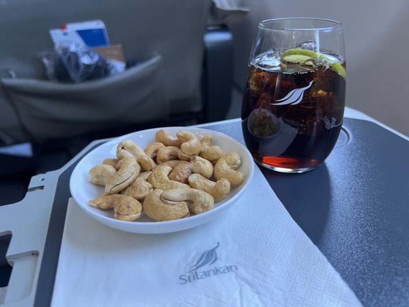 a plate of cashews and a glass of cola on a table