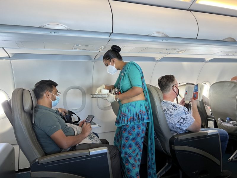 a woman in a blue dress and mask standing in a plane