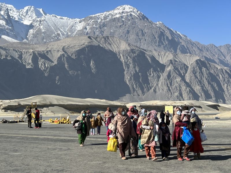 a group of people walking on a road with mountains in the background