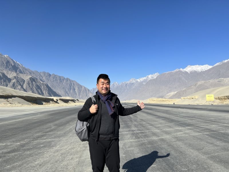 a man standing on a road with mountains in the background