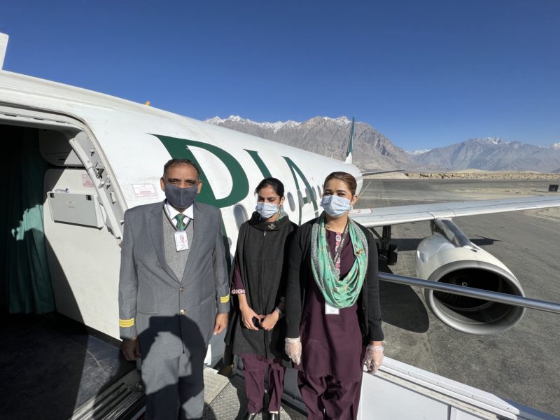 a group of people wearing face masks standing in front of an airplane