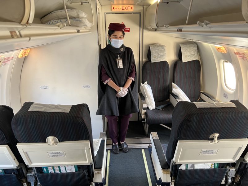 a woman in a mask and gloves standing in an airplane