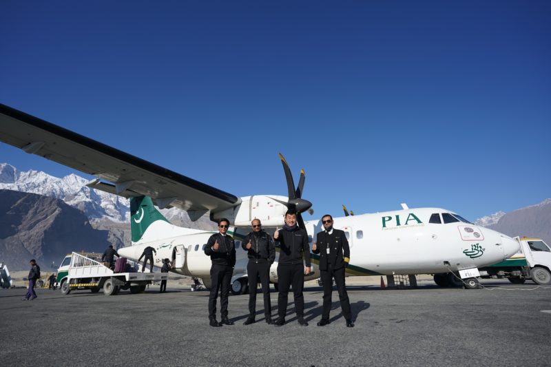 a group of men in black uniforms standing in front of an airplane