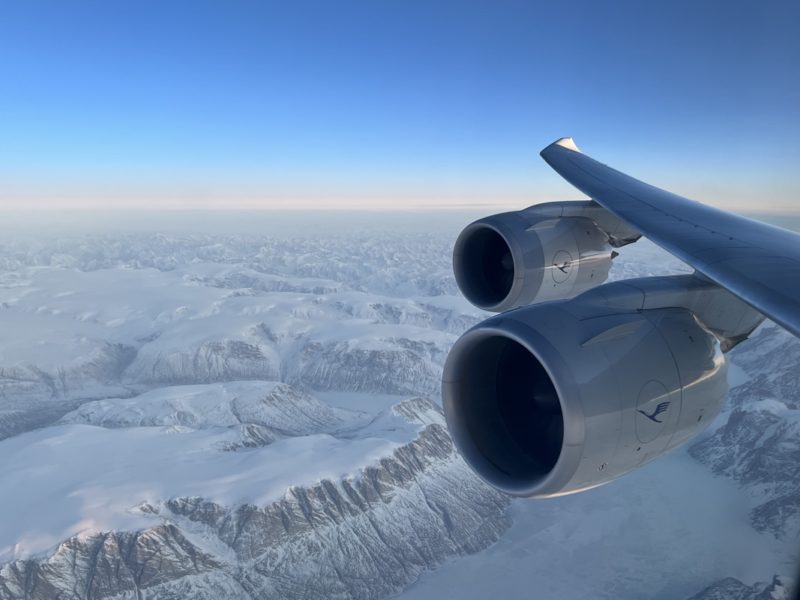 a plane wing with two engines above the snow covered mountains