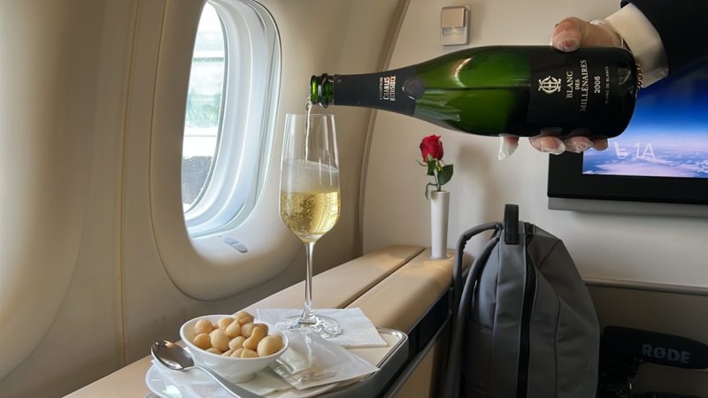 a person pouring champagne into a glass on an airplane