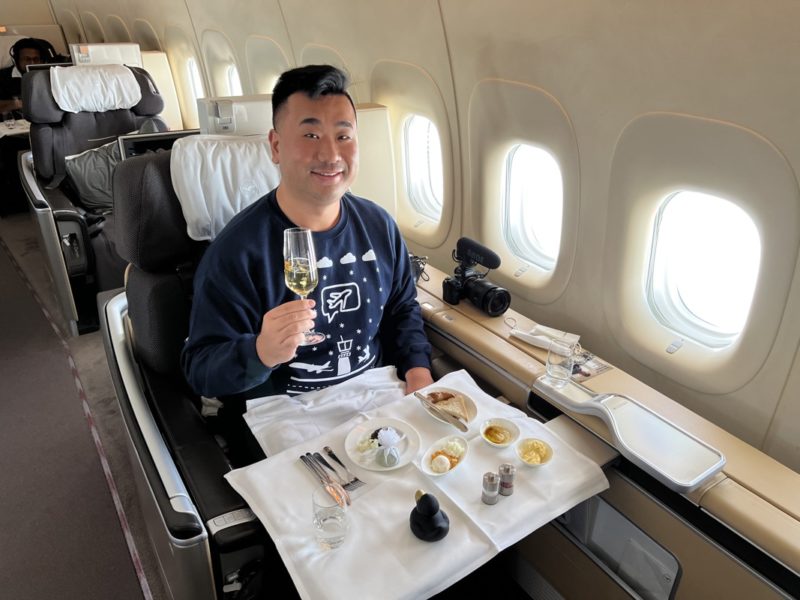 a man sitting in a chair with a tray of food and a glass of champagne