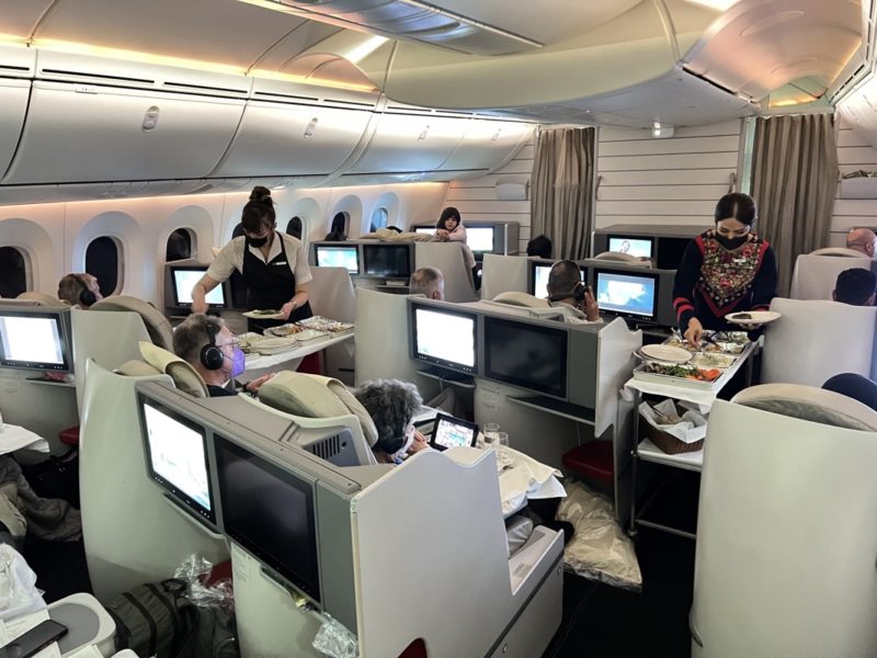 people in an airplane with people eating and sitting at tables