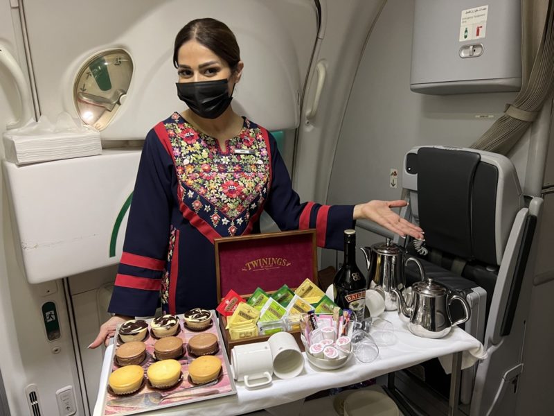a woman wearing a face mask standing in an airplane with a tray of food