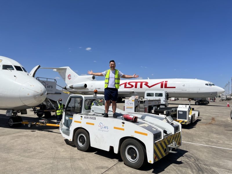 a man standing on a vehicle with a plane in the background