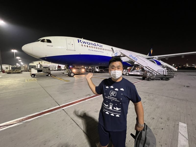 a man wearing a face mask standing in front of an airplane