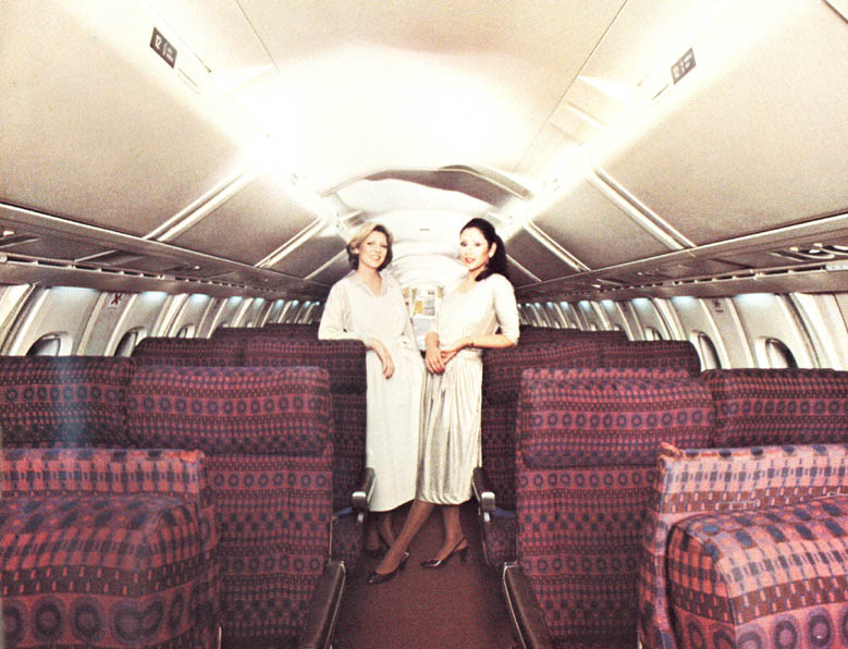 two women standing in the back of an airplane