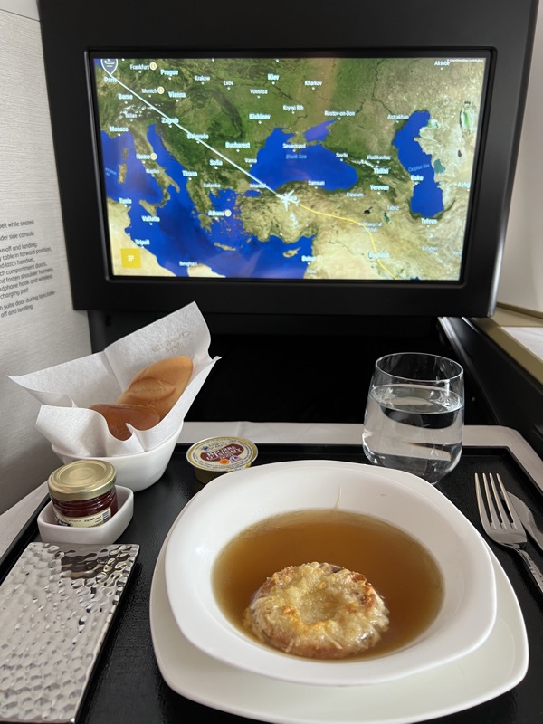 a plate of soup and a glass of water on a tray with a television