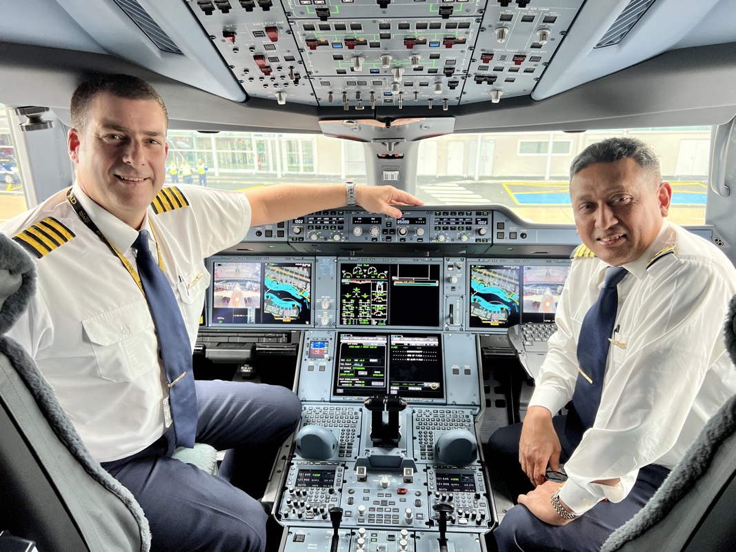 two men in uniform sitting in a cockpit