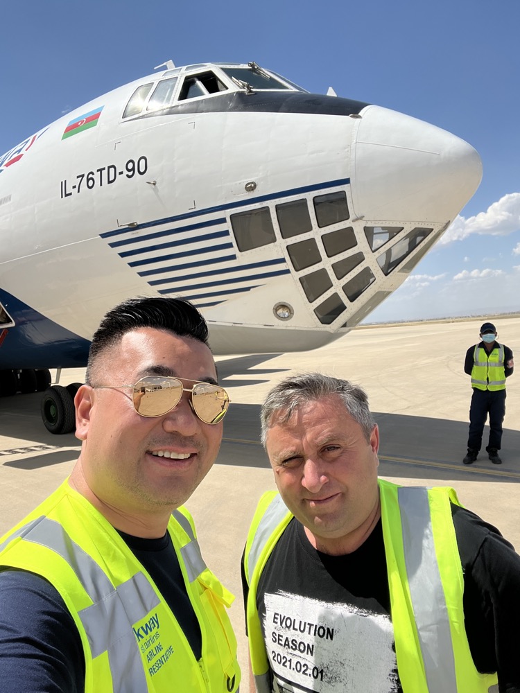 two men taking a selfie in front of a plane