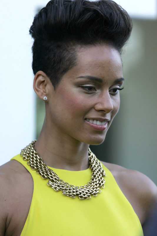 a woman with short hair wearing a yellow dress and a gold necklace