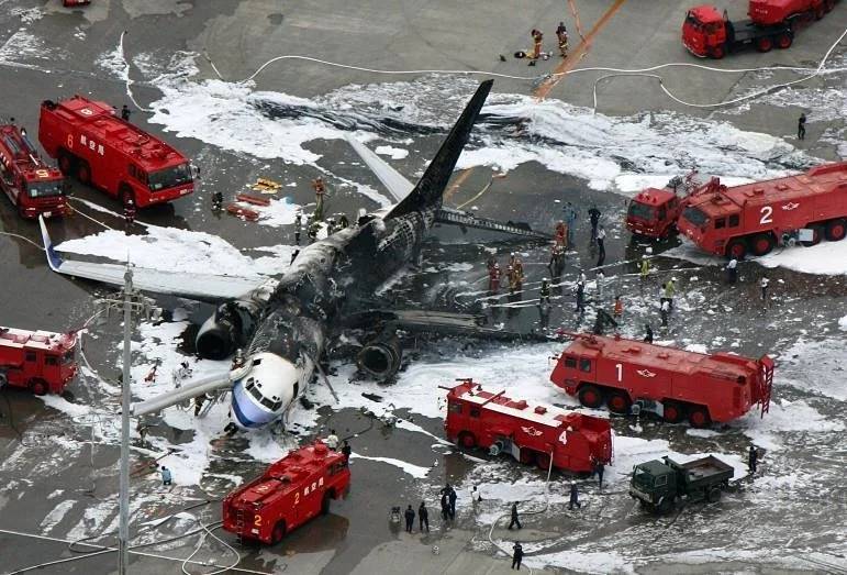 an airplane crashed on the ground with fire trucks and people around