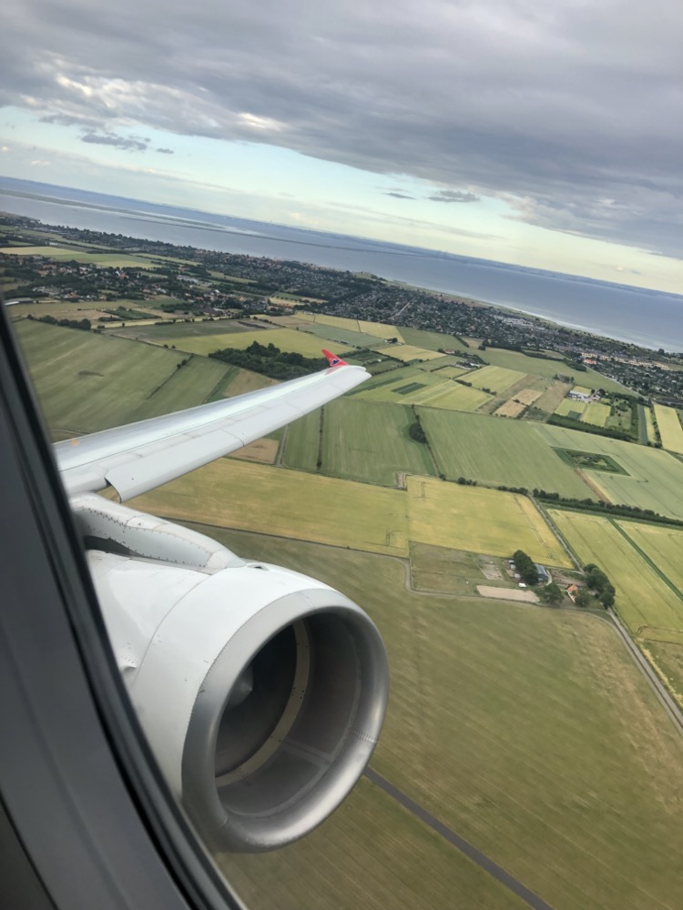 an airplane wing and view of land and water