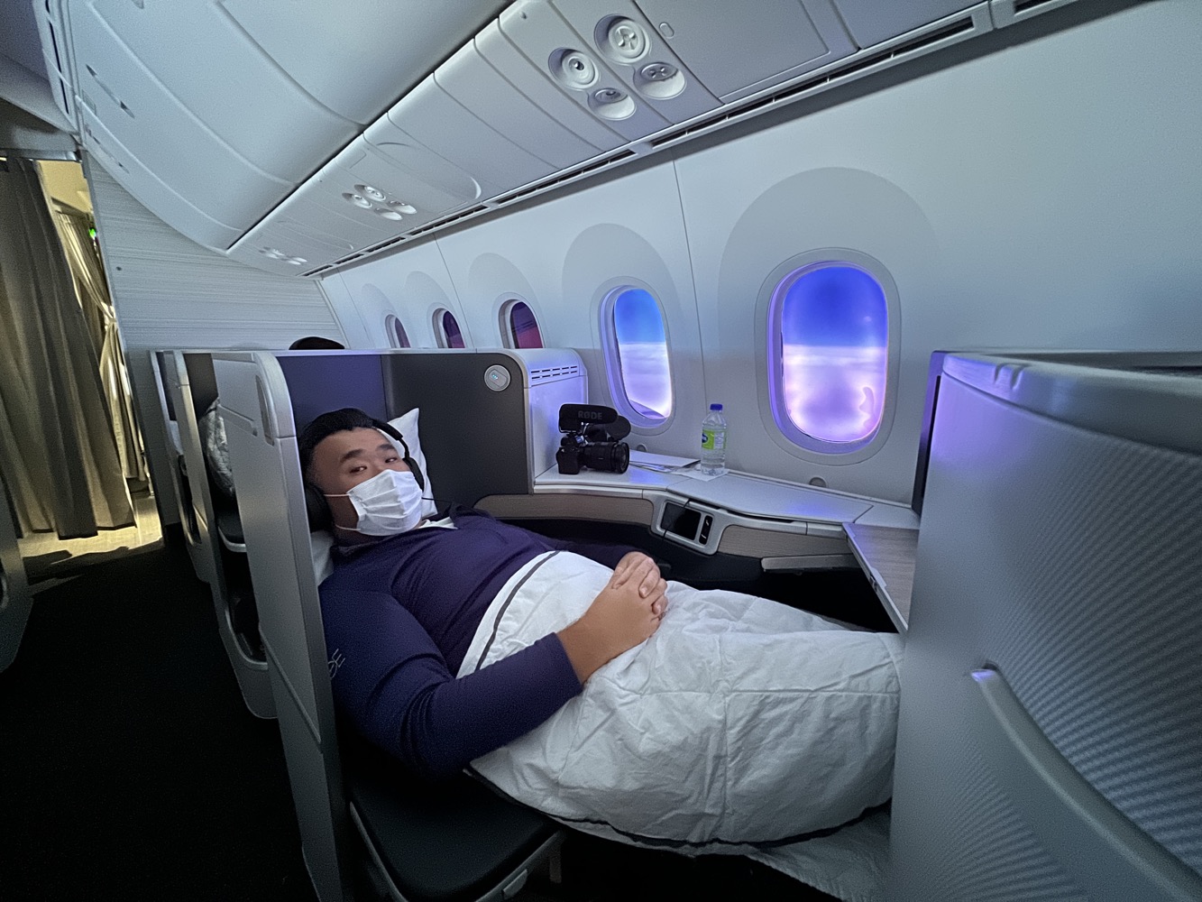 a man lying in a plane with a face mask