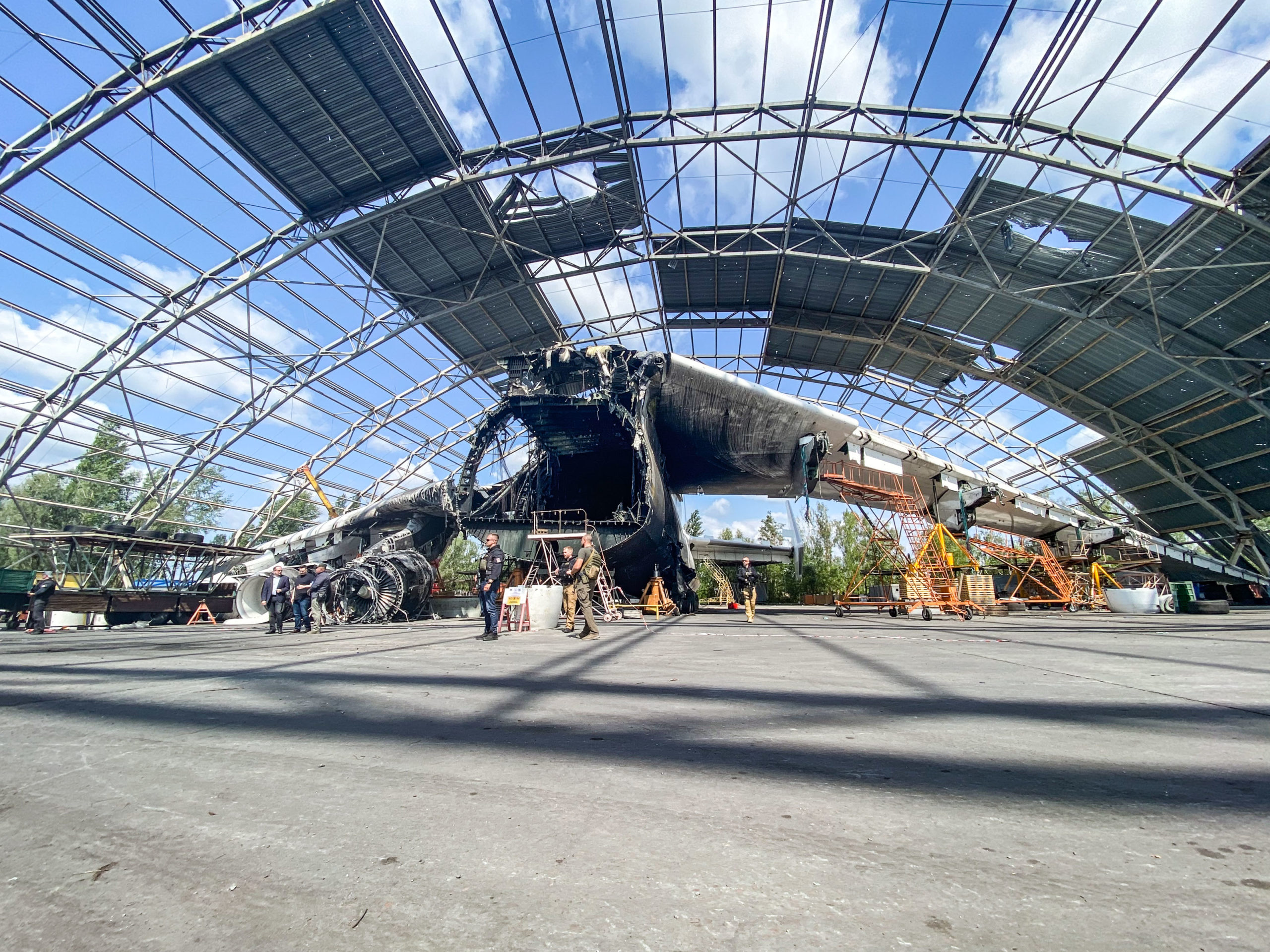 The An-225 is without its nose section and is still standing under a heavily damaged canopy. 