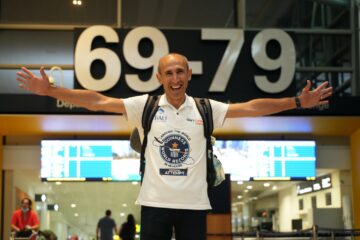 a man with his arms outstretched in front of a sign