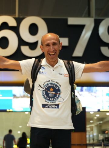 a man with his arms outstretched in front of a sign