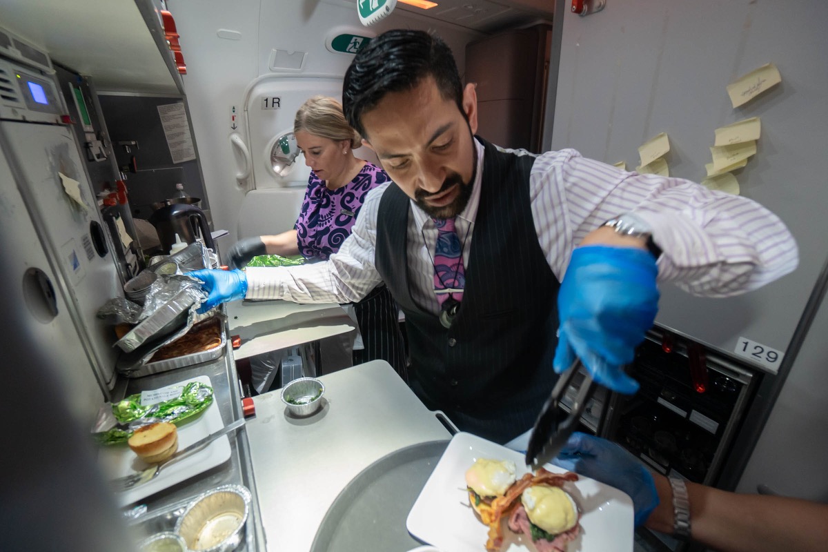 a man in a vest and gloves serving food