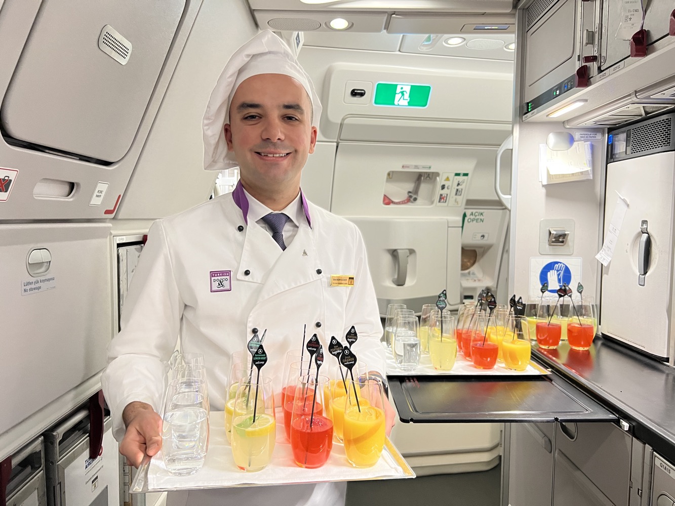 a man in a chef uniform holding a tray of drinks