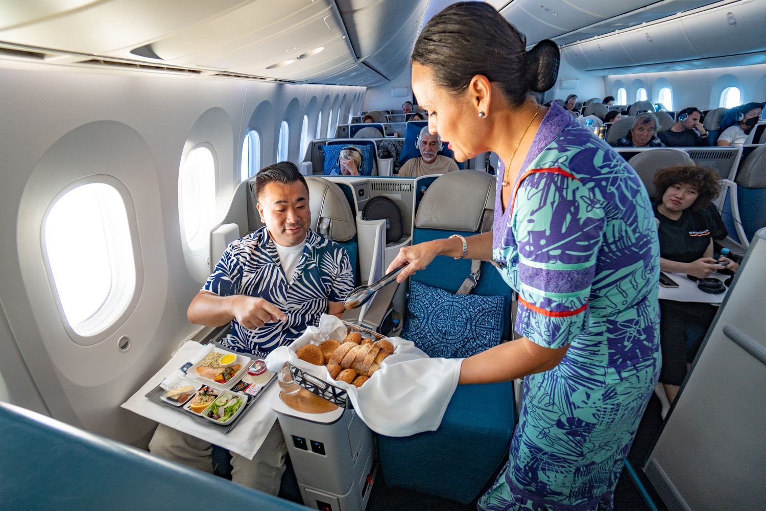 a woman serving food to a man on an airplane